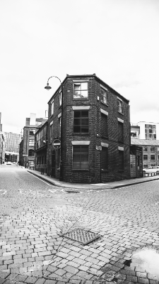 A black and white shot of a building cornering two back streets in Manchester